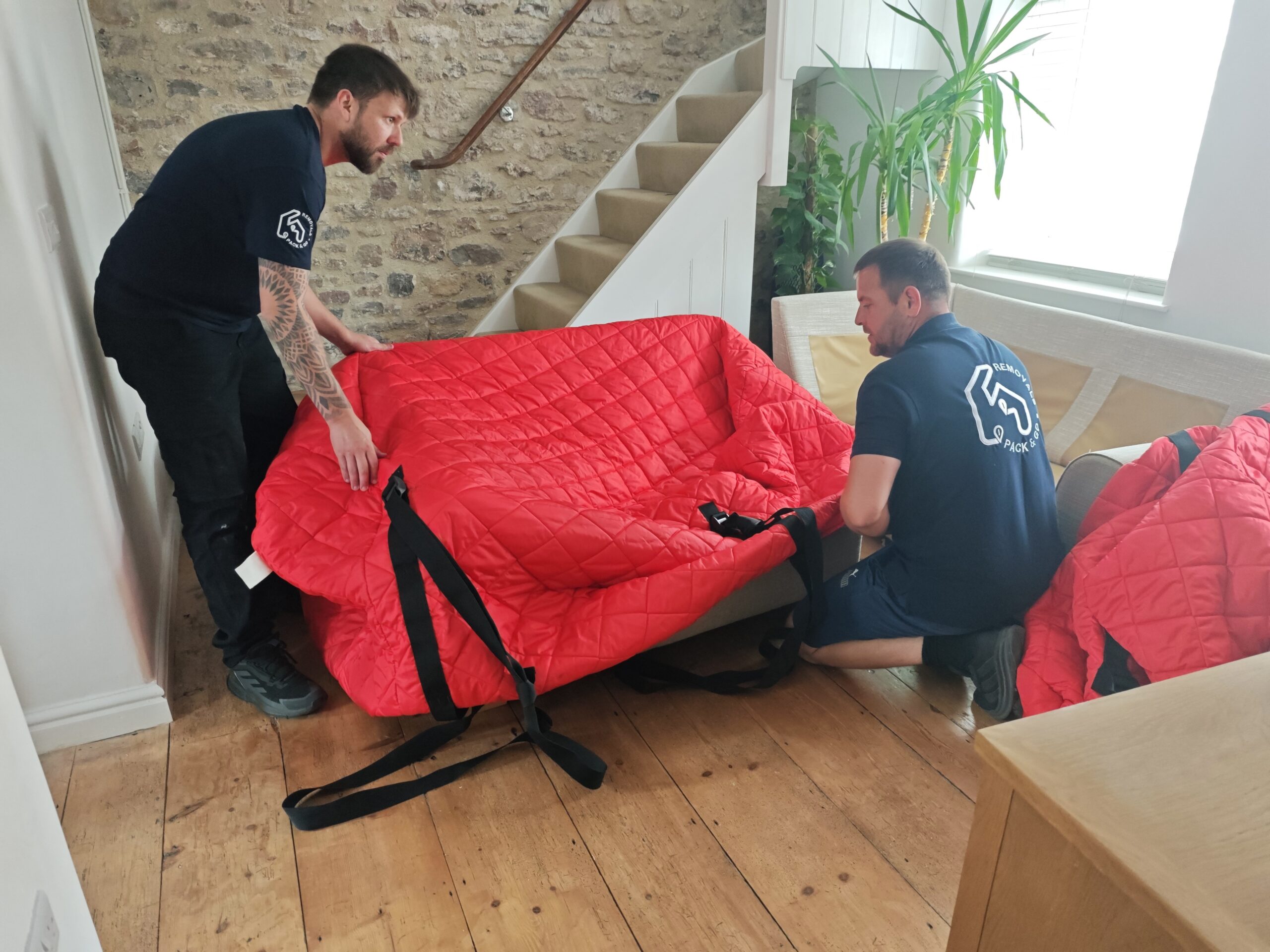 Professional movers carefully protecting and handling household furniture during a move.